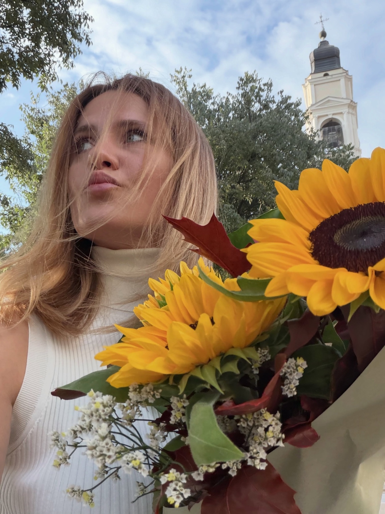 Ritratto ravvicinato di Valentina Morarasu con il mazzo di girasoli, il campanile sullo sfondo